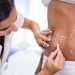 A specialist drawing contouring marks on a woman's abdomen for a body sculpting treatment.